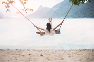 Carefree happy woman on swing on beautiful paradises beach
