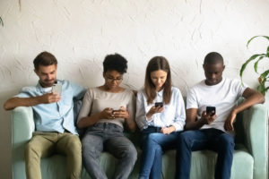 Four young people sitting on couch absorbed by smartphones